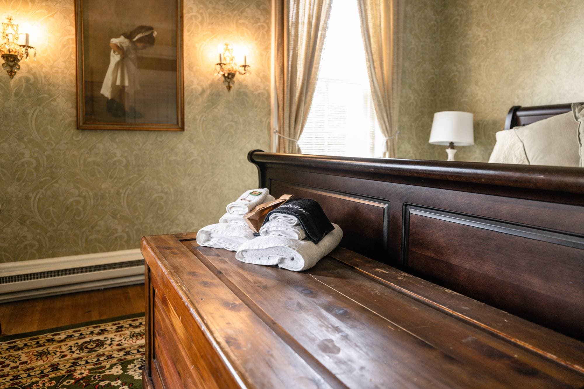 Sleigh bed footboard and wooden chest with white towels on top